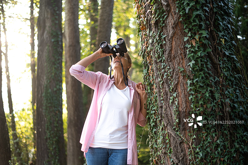 年长女性在徒步旅行时使用望远镜观察动物和事物图片素材