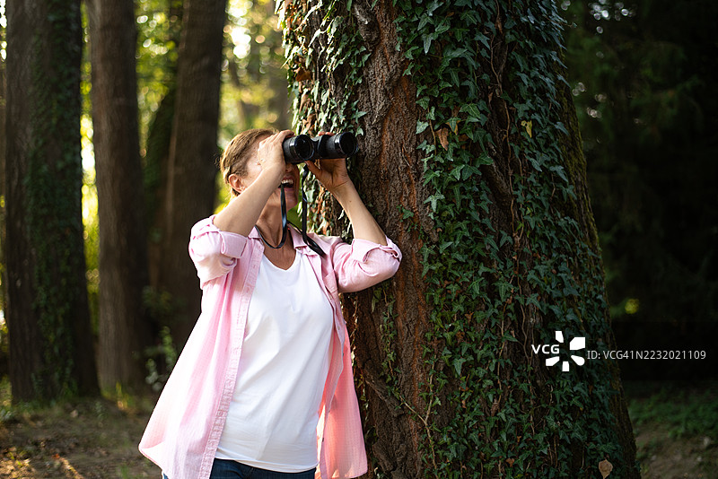 成熟的女性享受大自然，使用望远镜观察图片素材