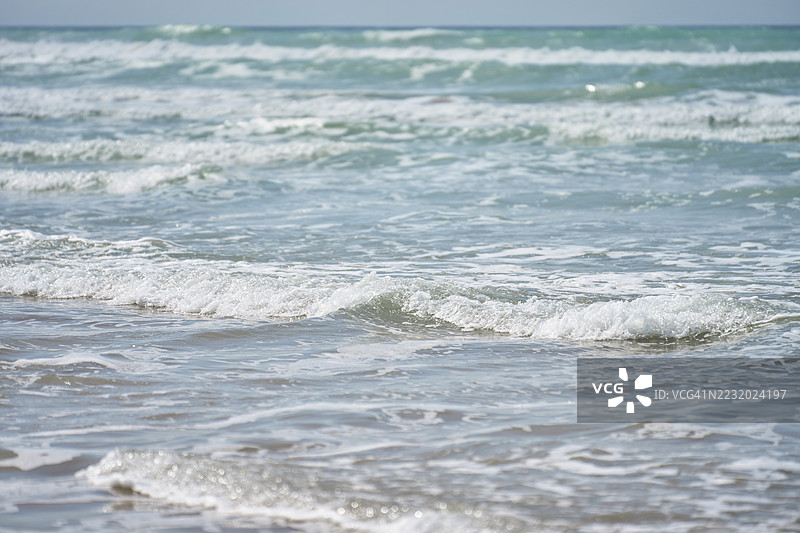 温暖阳光下，温柔的海浪拍打着海岸图片素材