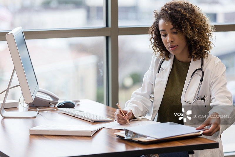 女医生在办公室的桌子上工作，使用电脑图片素材