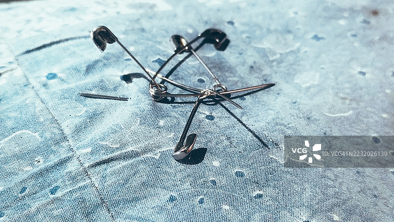 蓝色纹理布料上的安全别针特写图片素材