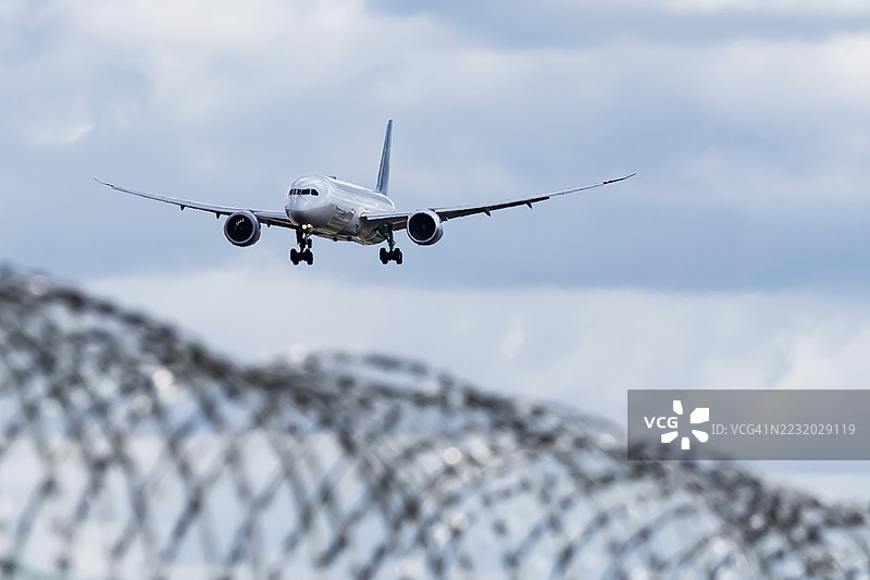 带刺铁丝网与空中飞来的客机图片素材