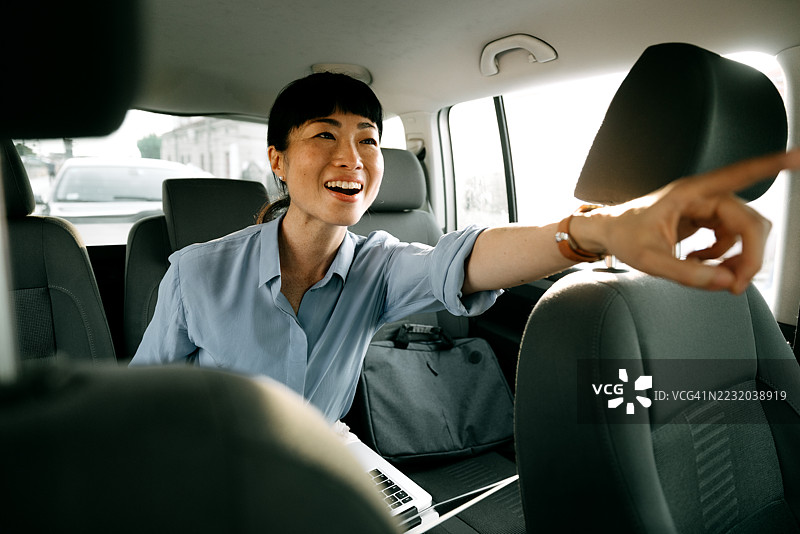 快乐的女性在汽车后座指着前方图片素材