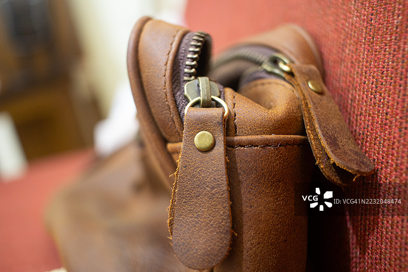 棕色皮革包的特写，配有黄铜拉链和肩带图片素材