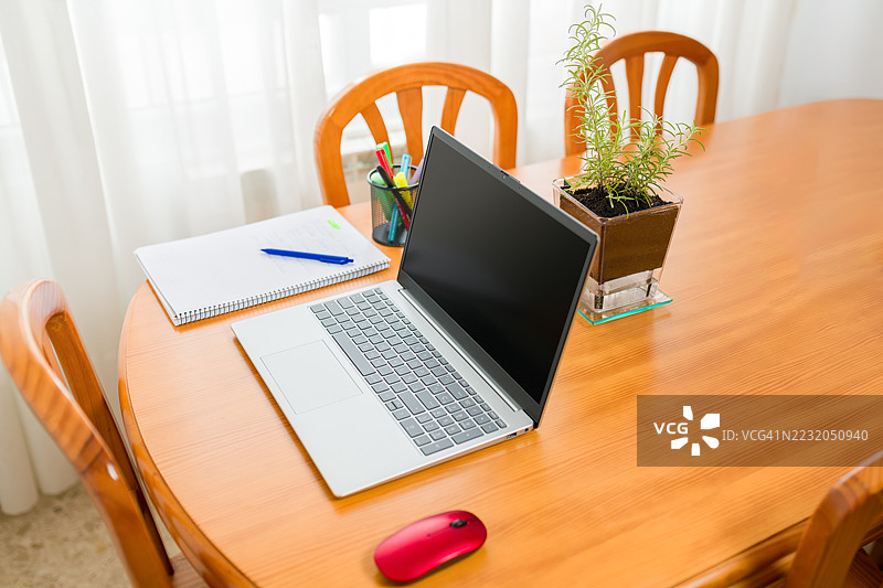 从高角度俯视木桌上的笔记本电脑、笔记本和盆栽植物图片素材