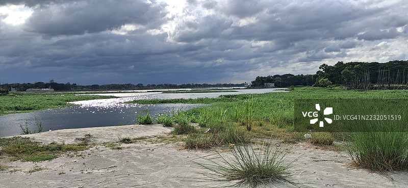 孟加拉国萨瓦尔的宁静河流风景在阴云密布的天空下图片素材