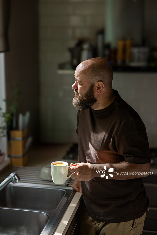 男人在家厨房水槽旁享受早晨咖啡图片素材
