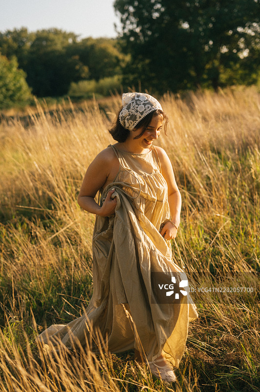 年轻女性在金色时光的田野中漫步图片素材