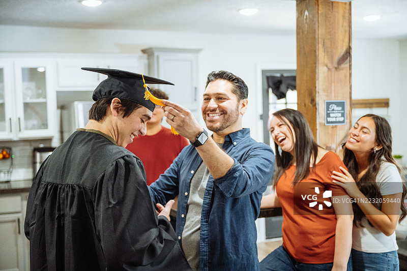 家庭毕业庆祝 - 父亲拥抱穿着毕业袍的儿子图片素材