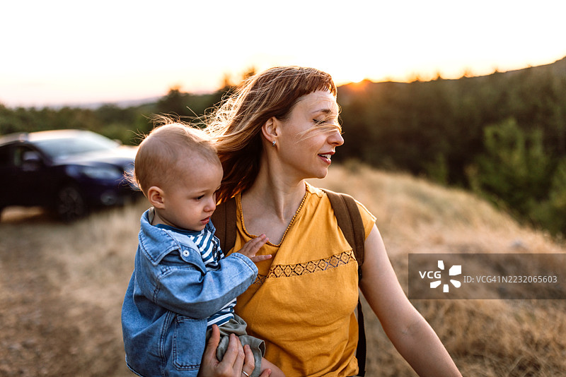 母亲和她的婴儿儿子在自然中享受日落散步。图片素材
