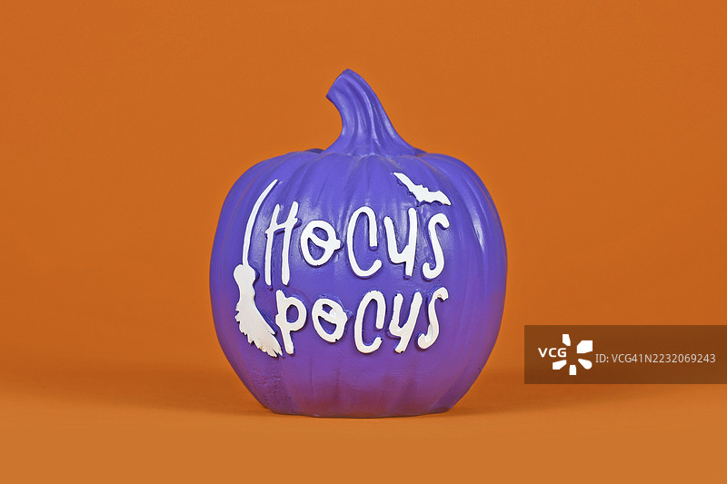紫色万圣节南瓜装饰，背景为橙色，上面写着“霍库斯·波库斯”图片素材