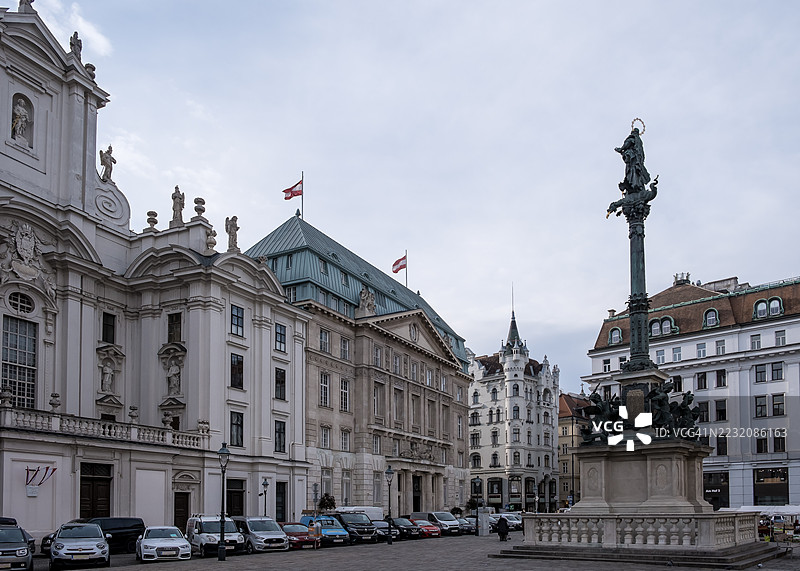 玛丽恩柱的景观，这座17世纪的瘟疫纪念柱矗立在教堂广场的教堂前，金色的圣母玛利亚雕像与教堂严峻的哥特式外立面形成鲜明对比。图片素材