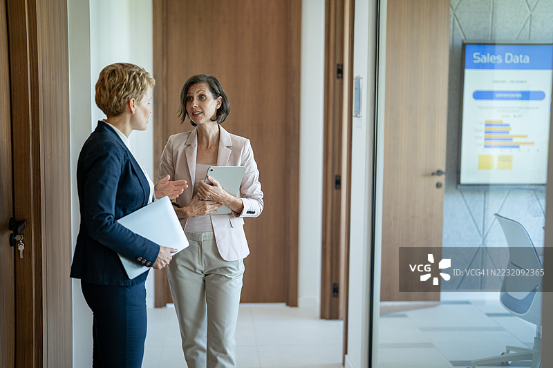 女商人在办公室走廊讨论销售数据图片素材