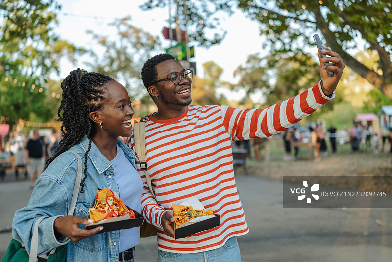 朋友们在户外节日上享受街头美食并自拍图片素材