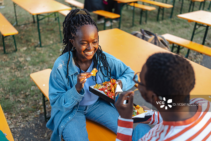 朋友们在户外活动中愉快地享用美食，互动欢快。图片素材