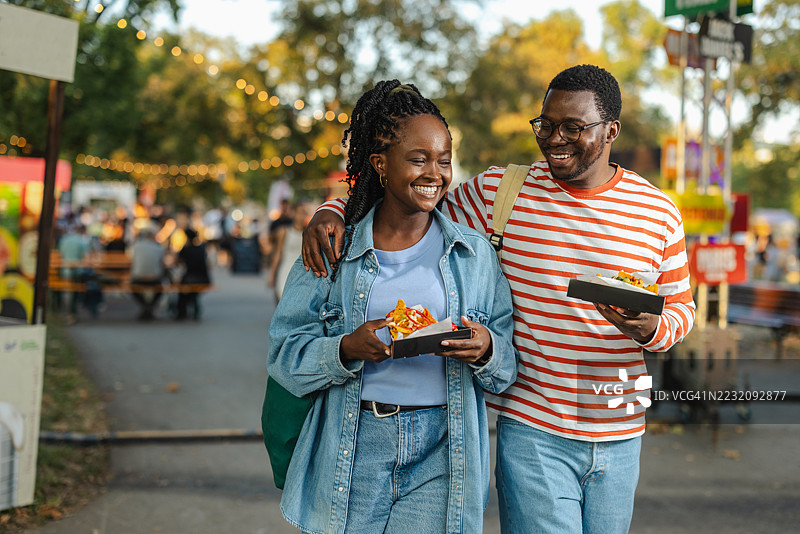 快乐的情侣在户外节日上一起享受街头美食图片素材