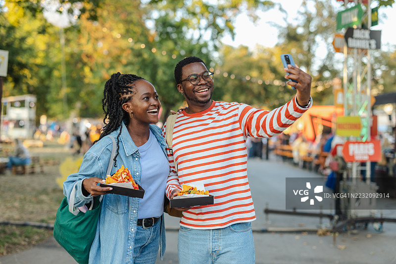 朋友们在户外节日上享受街头美食并自拍图片素材