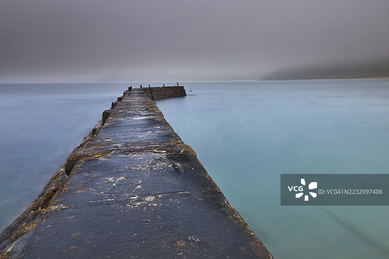 在英国康沃尔西部的兰兹角附近，塞农湾的防波堤在朦胧而阴暗的黎明时分的景象。图片素材