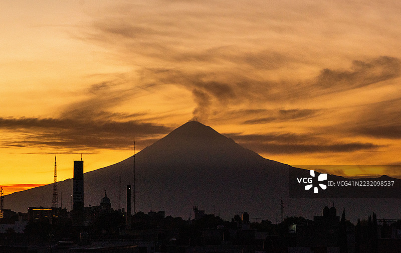 活跃的波波卡特佩特火山景观,伴随着来自墨西哥普埃布拉历史老城的烟雾柱图片素材