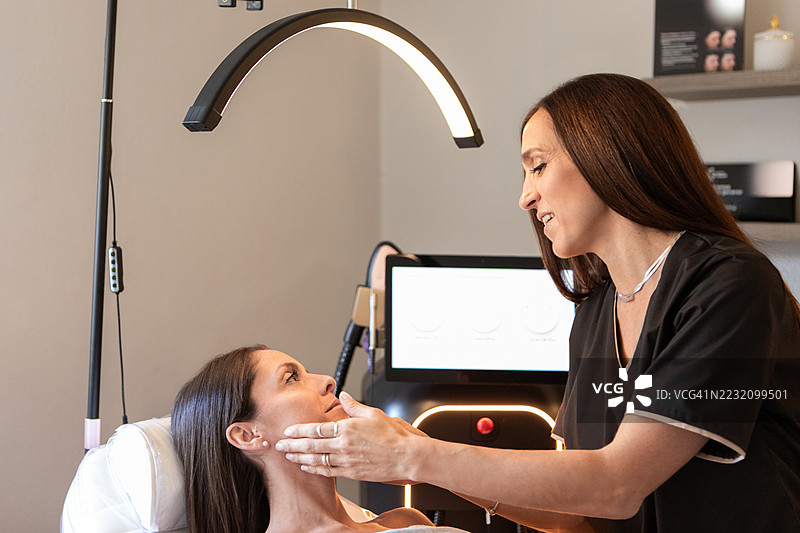 女皮肤科医生在诊所评估她的女性病人图片素材