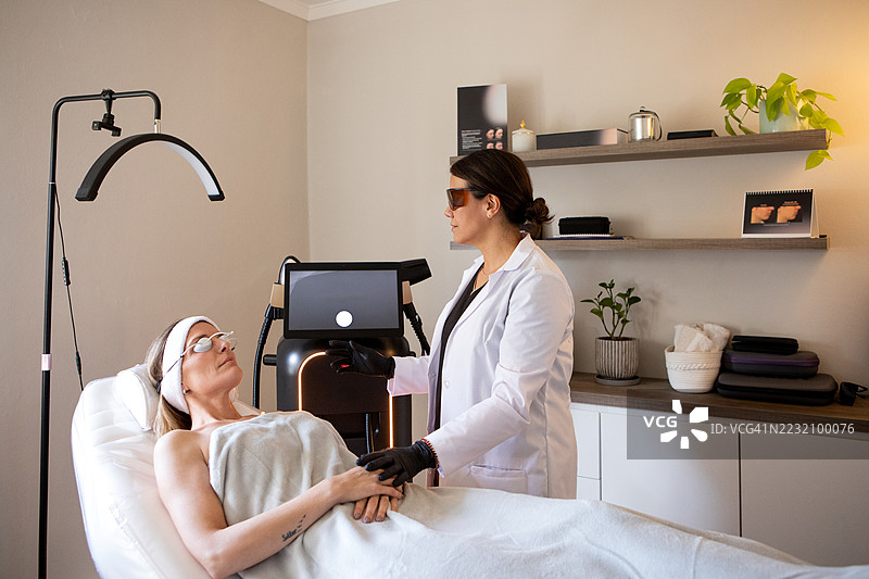 皮肤科医生在诊所为患者的面部应用尖端技术图片素材