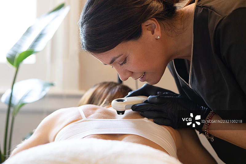 女皮肤科医生正在用皮肤镜检查她的病人图片素材