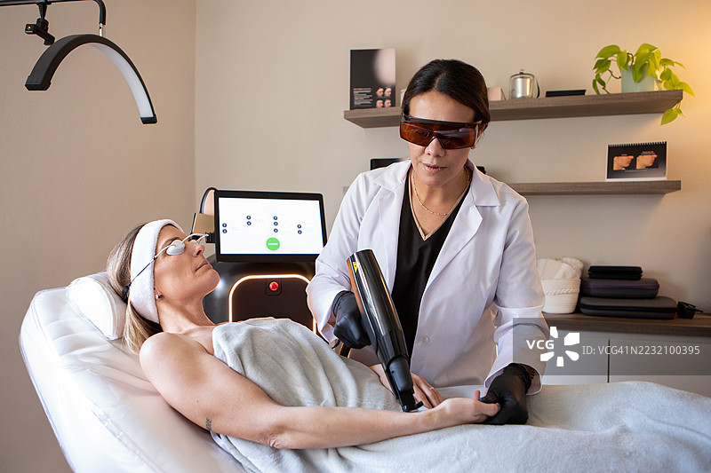 皮肤科医生在诊所为患者的面部应用尖端技术图片素材