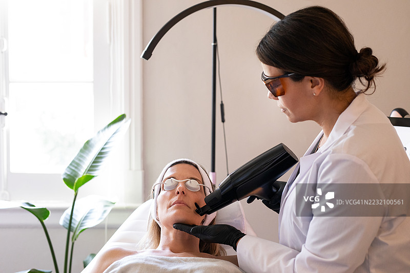 皮肤科医生在诊所为患者的面部应用尖端技术图片素材