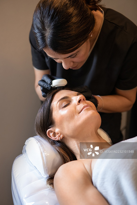 女皮肤科医生正在用皮肤镜检查她的病人图片素材