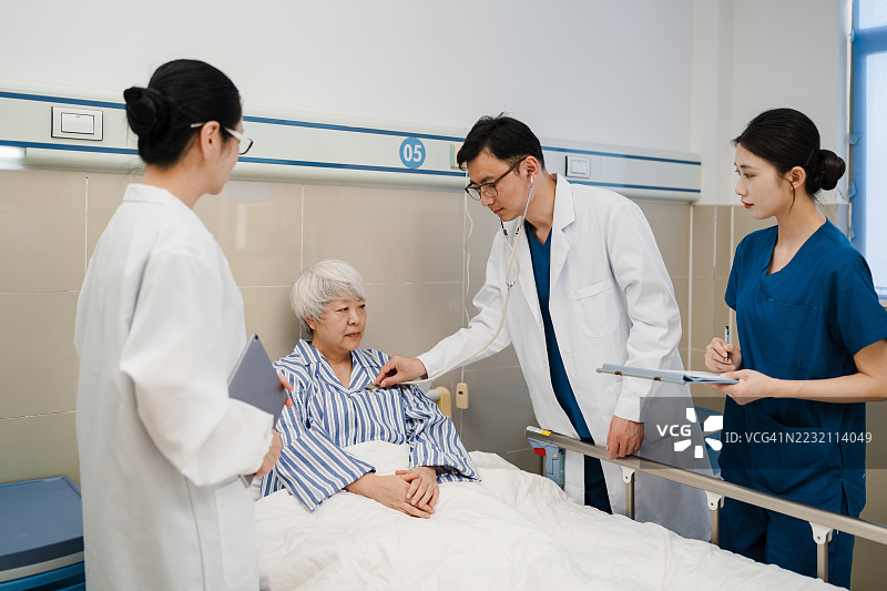 一群亚洲医生和护士在病房里检查一位病人。图片素材
