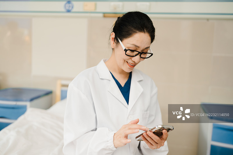 亚洲女性医生在工作场所使用智能手机。图片素材