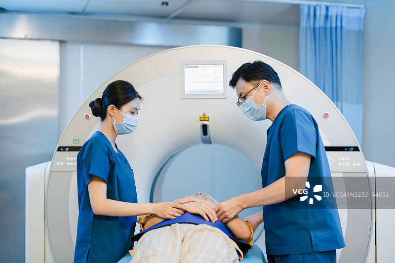 年轻的亚洲女性和男性护士在MRI扫描室操作MRI扫描机。女性医疗工作者在医疗扫描室内。医疗保健概念。图片素材