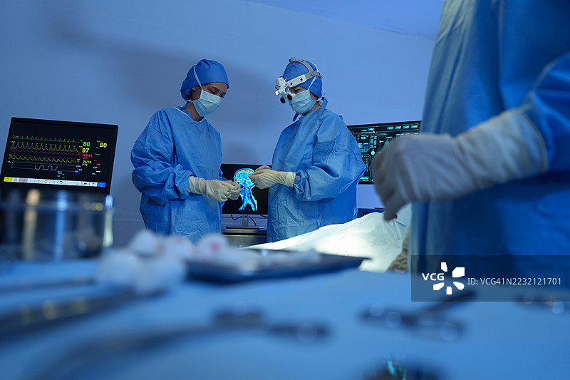 穿着虚拟现实（VR）头盔和手术服的外科医生在手术室内，现代手术室中的手术技术图片素材