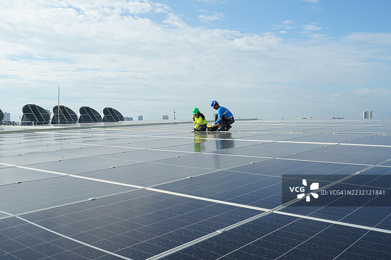 男性和女性工程师正在检查最近安装在高层建筑上的太阳能电池板。图片素材