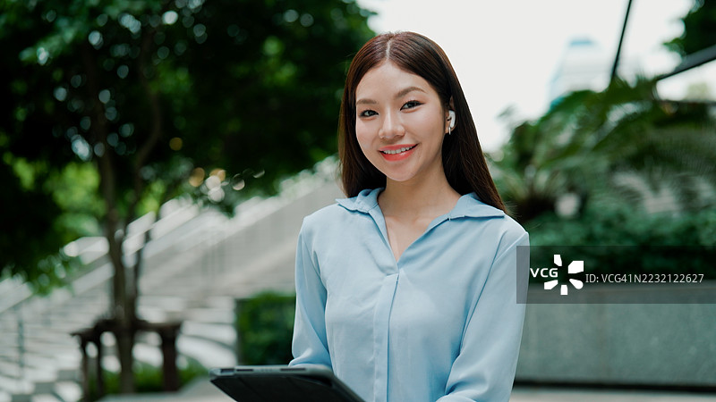 年轻的亚洲女性在户外工作空间中使用数字平板电脑工作。图片素材
