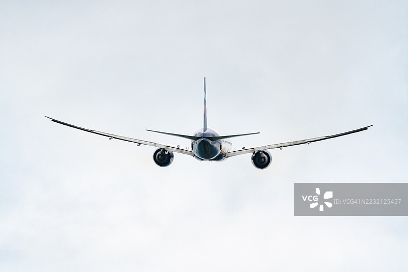 一架俄罗斯航空公司Aeroflot的波音777-300ER客机在阴云密布和下雨的天气中飞行,后视图。图片素材