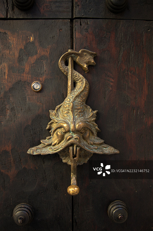 神话中的中世纪鱼形金属门环安装在一扇带钉的乡村木门上图片素材
