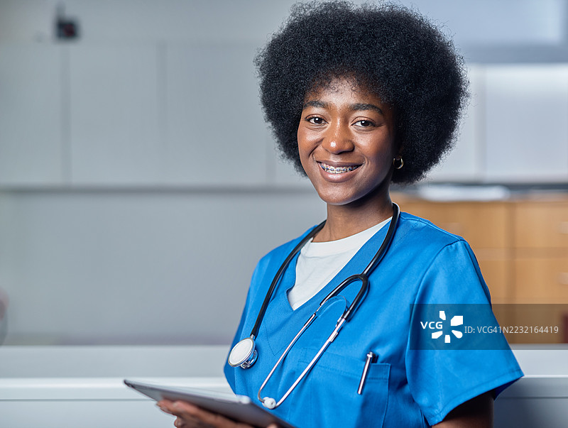 微笑的医疗专业人员在诊所接待处，身穿制服，佩戴听诊器图片素材