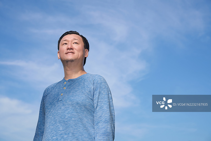 逆光抓拍的男性肖像，背景是夏日阳光和蓝天图片素材