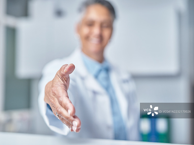 友好的医疗专业人士在前台接待区提供握手图片素材