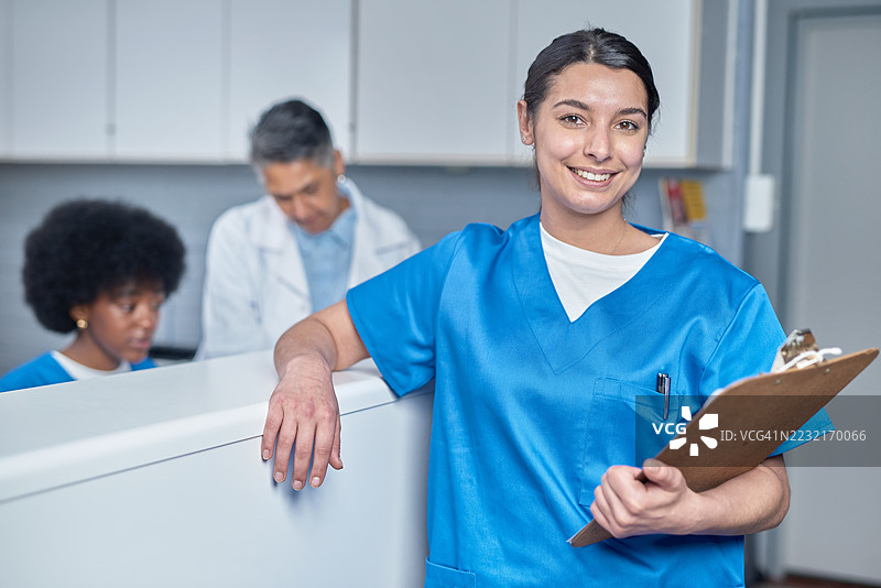 微笑的医疗专业人员在诊所接待区手持夹板图片素材