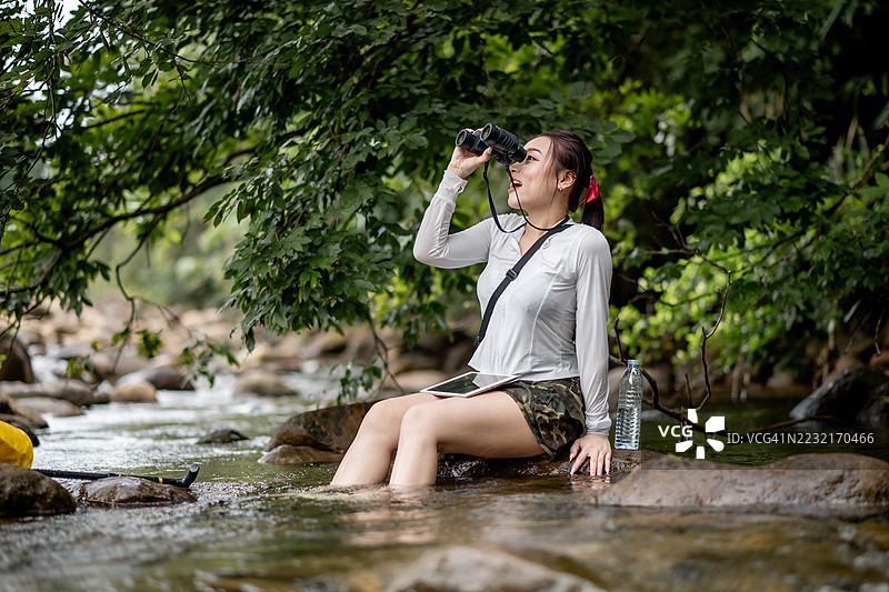 一位女性正在探索大自然，似乎在享受户外冒险，手持望远镜观察远方，表明她在探索或观鸟，与自然亲密接触。图片素材