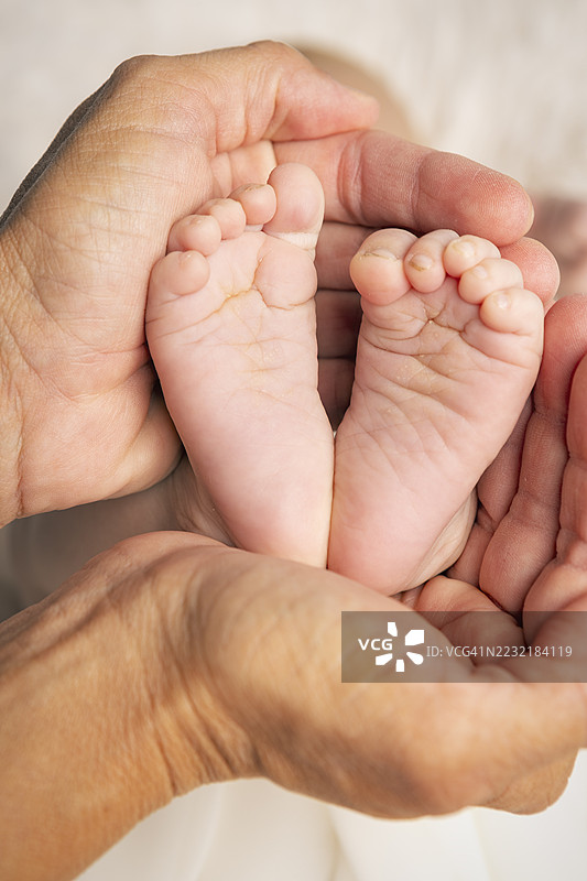 母亲手中抱着光滑的婴儿脚丫特写图片素材