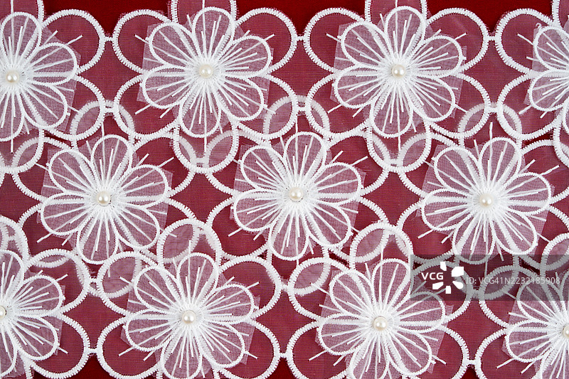 红色布料上的白色蕾丝纹理。图片素材