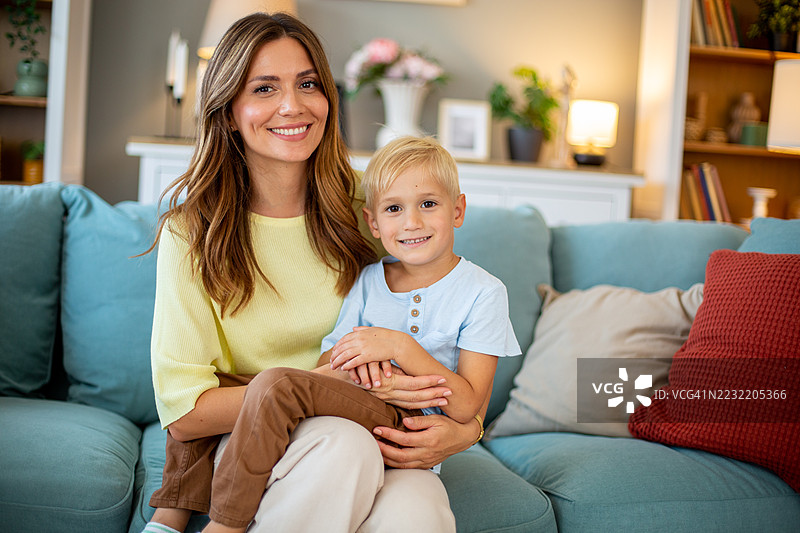 母亲和儿子在家里的沙发上微笑在一起图片素材