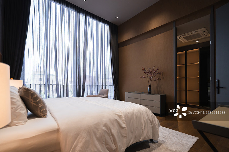 现代当代卧室展示了生物亲和设计，拥有自然光和大地色调。可持续的室内设计特点包括有机质感、极简美学和受“舒适”启发的温馨氛围。图片素材