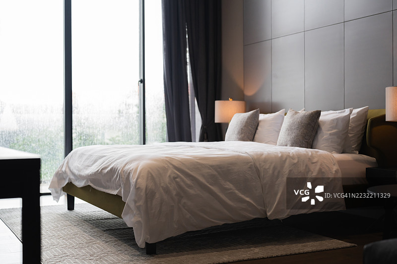 极简风格床铺特写，配有清新的白色床单和柔和的晨光。斯堪的纳维亚风格的卧室布置展示了“舒适”美学和自然光线，旨在营造注重健康的生活方式。图片素材