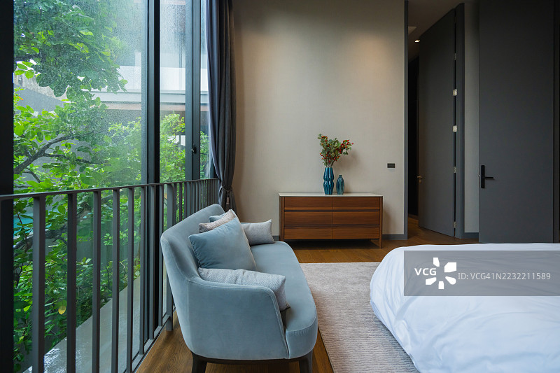 现代客厅展示了经过精心布置的家具，包括沙发、扶手椅和咖啡桌，沐浴在自然光下。现代家居室内展现了极简设计原则和生物亲和元素。图片素材