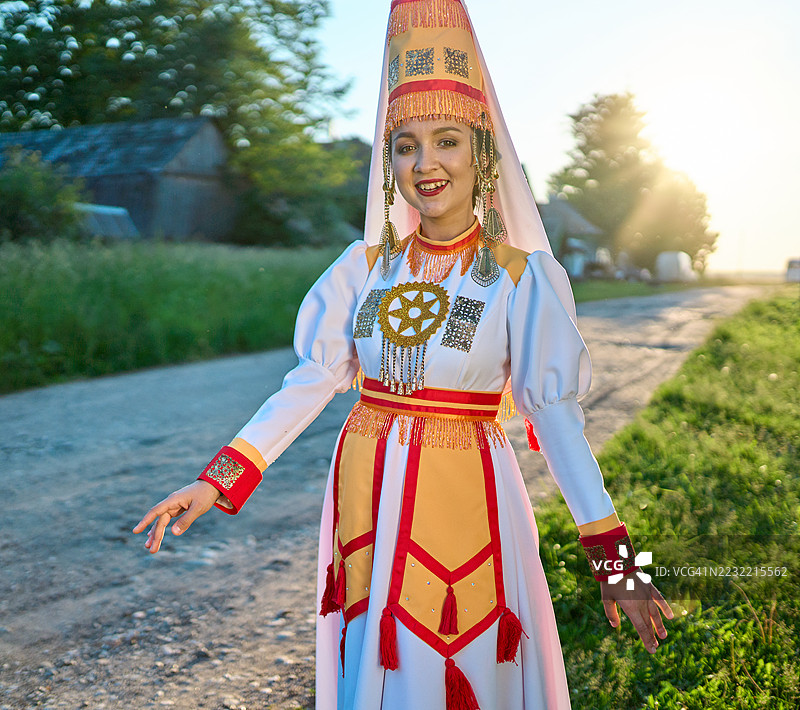 三分之四的肖像。迷人的年轻玛丽女性在乡村街道上摆出舞蹈姿势，微笑着看向镜头。图片素材