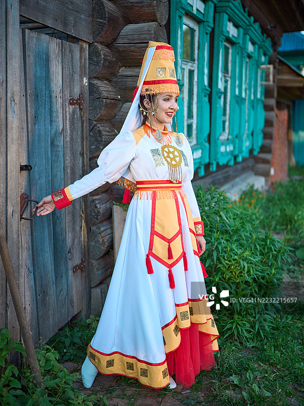 身穿传统服装的迷人玛丽年轻女性站在木屋的入口处图片素材